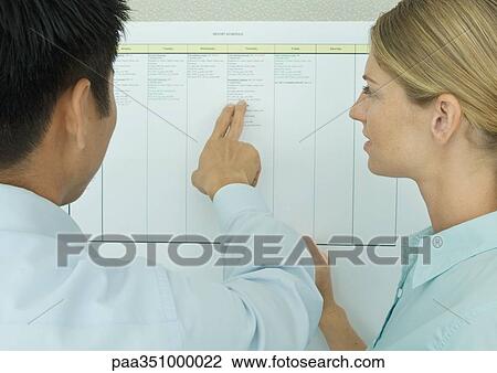 Two colleagues looking at chart on wall View Large Photo Image Stock Image - Two colleagues looking at chart on wall. Fotosearch