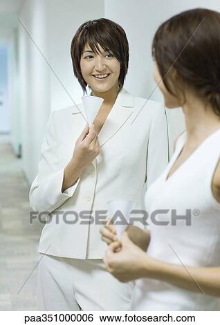 Two office workers holding cups and chatting in hallway View Large Photo Image Stock Photograph - Two office workers holding cups and chatting in hallway. Fotosearch