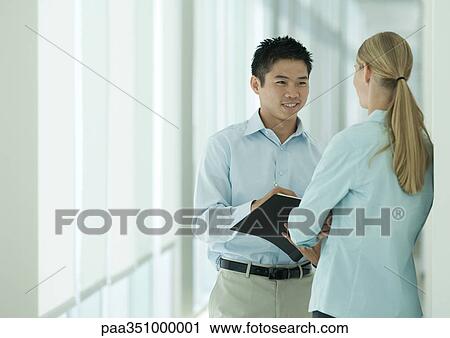 Stock Image - Two office workers talking in corridor. Fotosearch