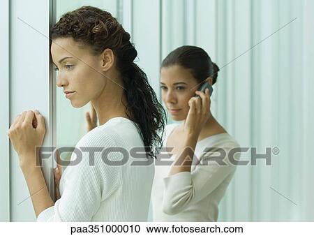 Woman looking out window while second woman phones View Large Photo Image Stock Image - Woman looking out window while second woman phones. Fotosearch