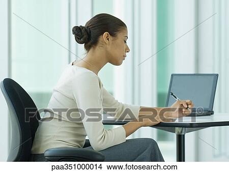Woman sitting at desk, writing View Large Photo Image Picture - Woman sitting at desk, writing. Fotosearch