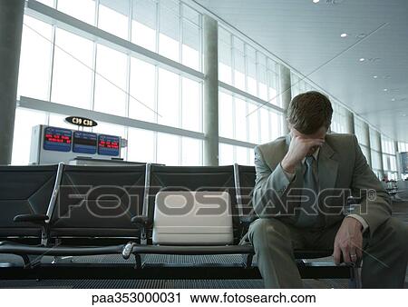 Businessman sitting in airport lounge, holding head View Large Photo Image Stock Image - Businessman sitting in airport lounge, holding head. Fotosearch