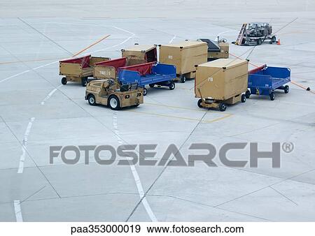 Luggage trucks and oontainers on airport runway View Large Photo Image Stock Photo - Luggage trucks and oontainers on airport runway. Fotosearch