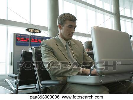 Stock Photograph - Man looking in open briefcase in airport lounge. Fotosearch