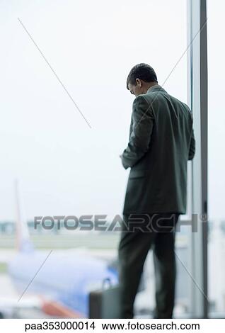 Man standing looking down, airplane in background View Large Photo Image Picture - Man standing looking down, airplane in background. Fotosearch
