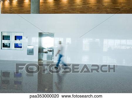 Stock Image - Man walking through airport, blurred motion. Fotosearch