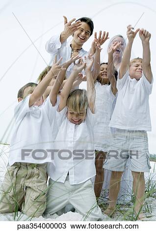 Stock Image - Beach wedding, children and groom throwing rice in air. Fotosearch