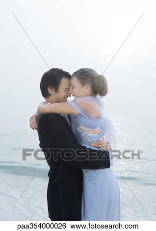 Stock Photograph - Bride and groom embracing on beach. Fotosearch