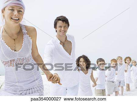 Bride and groom holding hands with line of children on beach View Large Photo Image Stock Photo - Bride and groom holding hands with line of children on beach. Fotosearch
