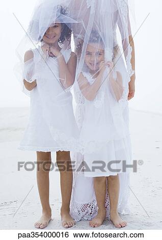 Flower girls standing underneath bride's veil on beach View Large Photo Image Stock Photograph - Flower girls standing underneath bride's veil on beach. Fotosearch
