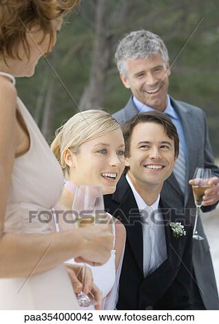 Outdoor wedding party, young bride and grooming standing between mature man and woman View Large Photo Image Stock Image - Outdoor wedding party, young bride and grooming standing between mature man and woman. Fotosearch