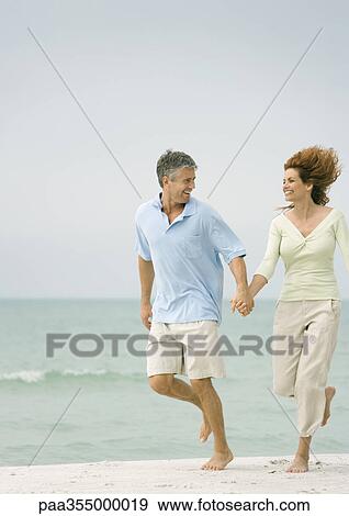 Mature couple running on beach, hand in hand View Large Photo Image Stock Photo - Mature couple running on beach, hand in hand. Fotosearch