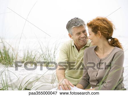 Mature couple sitting on beach View Large Photo Image Stock Photo - Mature couple sitting on beach . Fotosearch