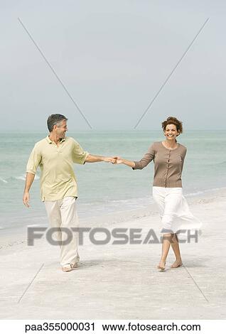 Mature couple walking on beach, holding hands View Large Photo Image Stock Image - Mature couple walking on beach, holding hands. Fotosearch