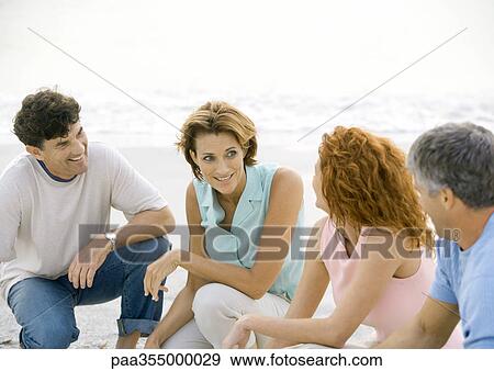 Two mature couples crouching on beach View Large Photo Image Stock Photo - Two mature couples crouching on beach. Fotosearch