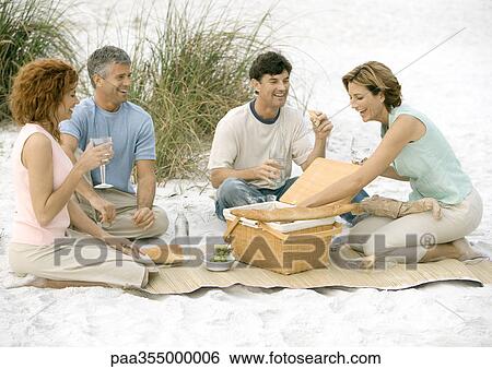 Stock Photograph - Two mature couples having picnic on beach . Fotosearch