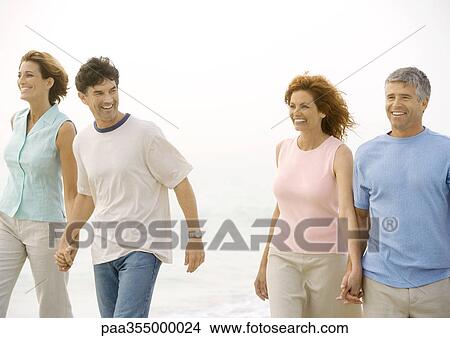 Picture - Two mature couples walking on beach. Fotosearch