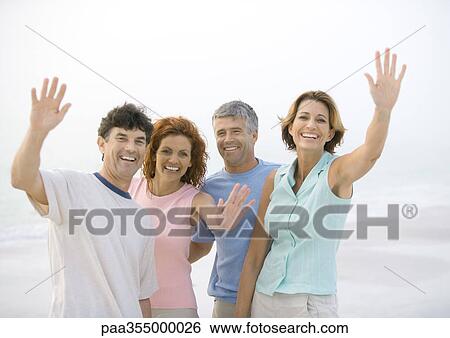 Stock Photograph - Two mature couples waving on beach. Fotosearch