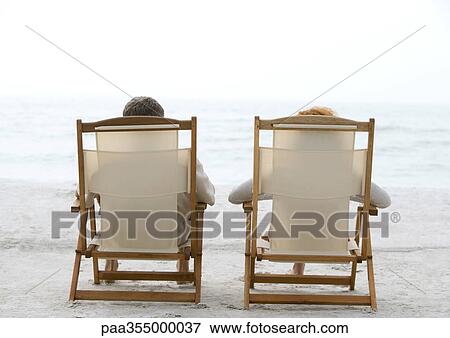 Two people sitting in beach chairs, rear view View Large Photo Image Stock Photo - Two people sitting in beach chairs, rear view. Fotosearch