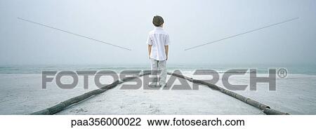 Boy standing in path on beach, facing horizon, rear view View Large Photo Image Stock Image - Boy standing in path on beach, facing horizon, rear view. Fotosearch