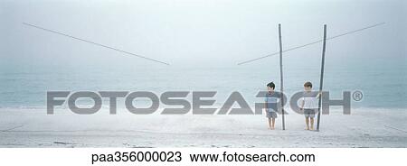 Boys standing on beach, holding big sticks View Large Photo Image Stock Image - Boys standing on beach, holding big sticks. Fotosearch