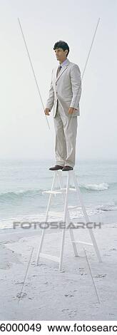 Businessman standing on top of stepladder, on beach View Large Photo Image Stock Photo - Businessman standing on top of stepladder, on beach. Fotosearch