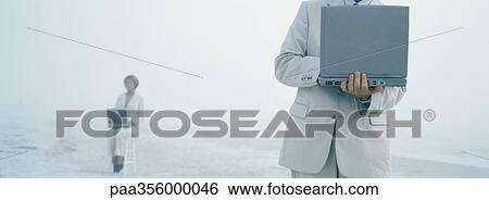 Stock Photograph - Businesspeople using laptops on beach. Fotosearch