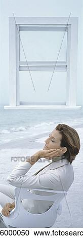 Businesswoman sitting on chair on beach with eyes closed, open window in background View Large Photo Image Stock Image - Businesswoman sitting on chair on beach with eyes closed, open window in background. Fotosearch
