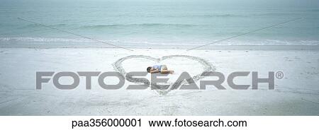 Child lying inside heart drawn on beach View Large Photo Image Stock Image - Child lying inside heart drawn on beach. Fotosearch
