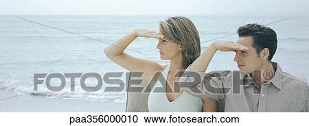 Couple looking toward distance on beach View Large Photo Image Stock Image - Couple looking toward distance on beach. Fotosearch
