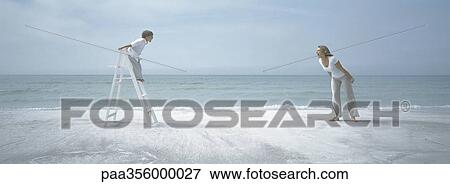 On beach, boy standing on ladder facing woman standing on sand, both screaming View Large Photo Image Stock Photo - On beach, boy standing on ladder facing woman standing on sand, both screaming. Fotosearch