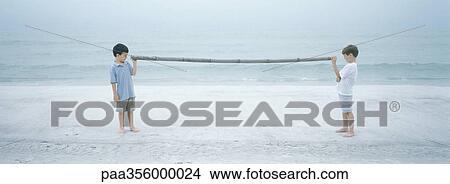Two boys holding either end of stick, on beach View Large Photo Image Picture - Two boys holding either end of stick, on beach. Fotosearch