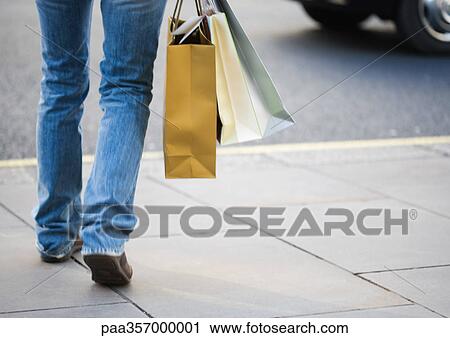 Person walking with shopping bags, low section View Large Photo Image Stock Image - Person walking with shopping bags, low section. Fotosearch