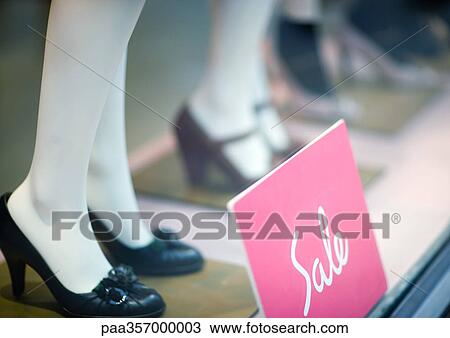 Stock Image - Sale sign by mannequins' feet in shop window. Fotosearch