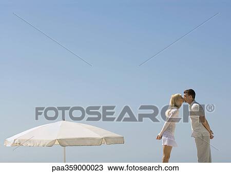 Couple kissing next to parasol View Large Photo Image Stock Image - Couple kissing next to parasol. Fotosearch
