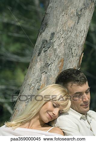 Couple leaning against tree, napping View Large Photo Image Stock Photography - Couple leaning against tree, napping. Fotosearch
