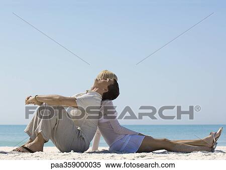 Couple sitting back to back on beach View Large Photo Image Stock Photography - Couple sitting back to back on beach. Fotosearch