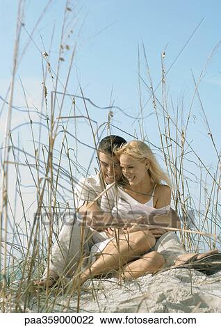 Couple sitting in dune grass, embracing View Large Photo Image Stock Image - Couple sitting in dune grass, embracing. Fotosearch