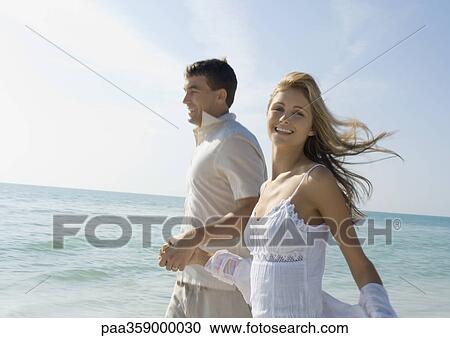 Stock Image - Couple walking on beach. Fotosearch