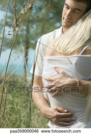 Stock Photograph - Man embracing woman, eyes closed. Fotosearch