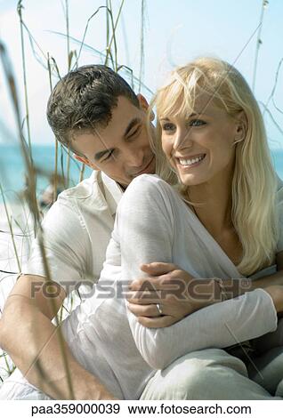 Stock Photo - Man holding woman on beach. Fotosearch