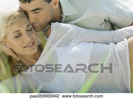 Stock Image - Man kissing woman lying on side. Fotosearch