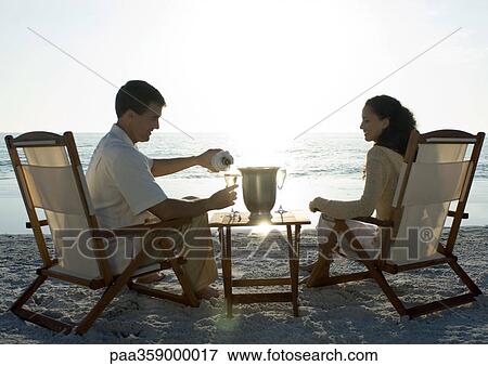 Newlyweds, husband serving wife champagne on beach View Large Photo Image Stock Photo - Newlyweds, husband serving wife champagne on beach. Fotosearch