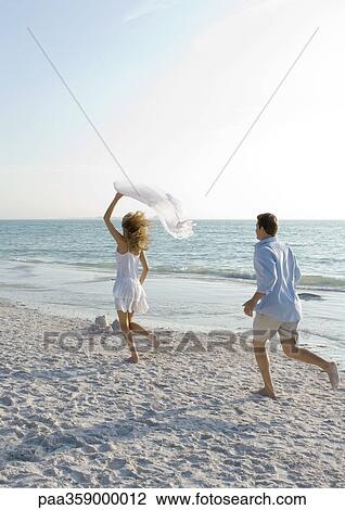 Newlyweds, man chasing woman on beach View Large Photo Image Stock Image - Newlyweds, man chasing woman on beach. Fotosearch
