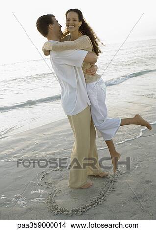 Newlyweds, man picking up woman on beach View Large Photo Image Picture - Newlyweds, man picking up woman on beach. Fotosearch