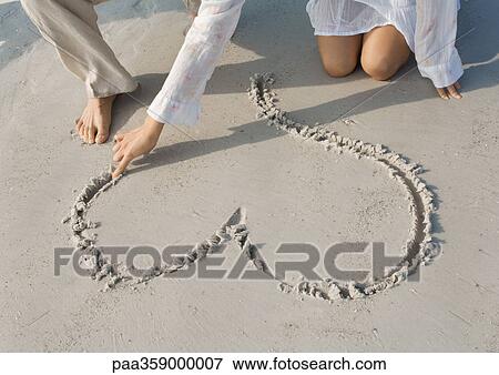 Woman drawing heart in sand on beach, partial view View Large Photo Image Stock Photo - Woman drawing heart in sand on beach, partial view. Fotosearch