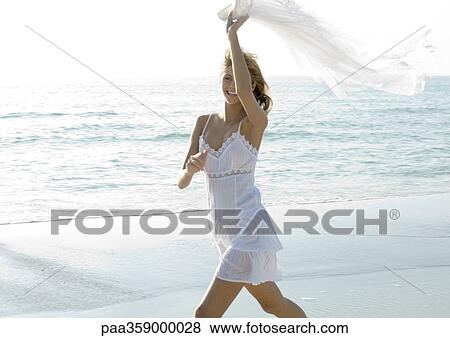 Woman on beach, holding up piece of clothing in wind View Large Photo Image Stock Photo - Woman on beach, holding up piece of clothing in wind. Fotosearch