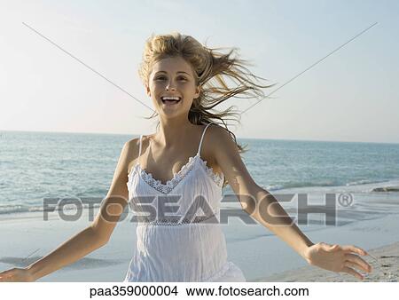 Young woman running with arms out on beach View Large Photo Image Picture - Young woman running with arms out on beach. Fotosearch