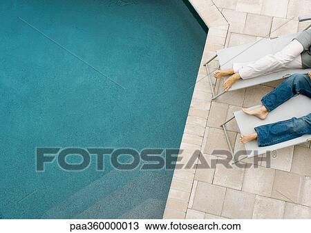 Stock Image - Couple lounging by pool, cropped. Fotosearch
