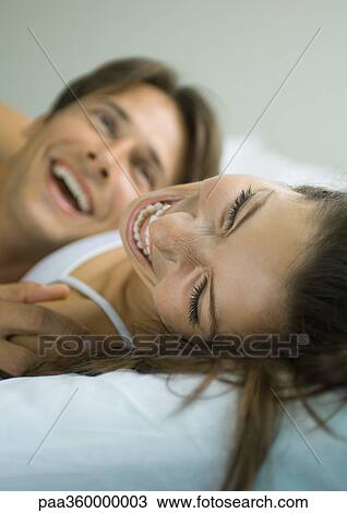 Couple lying in bed, laughing View Large Photo Image Stock Image - Couple lying in bed, laughing. Fotosearch